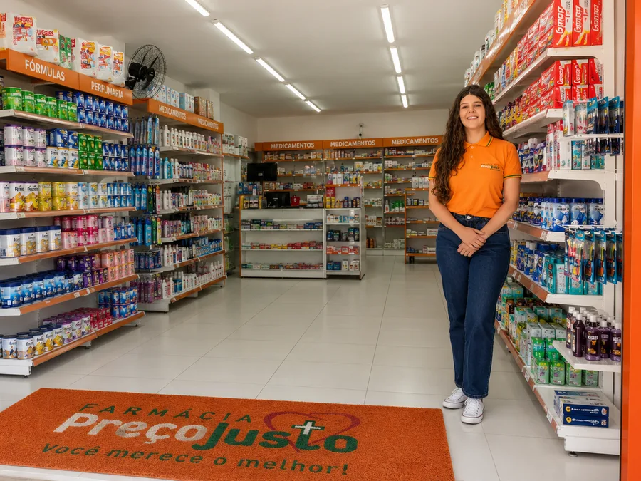 Atendente da Farmácia Preço Justo mostrando produtos de perfumaria